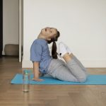 una ragazzina con la sindrome di down pratica sorridendo lo yoga sul suo tappetino